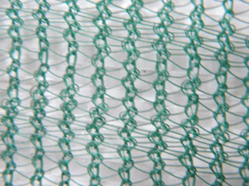 Agricultural shade netting mesh over a greenhouse structure